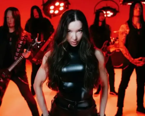 Wokalistka zespołu Arch Enemy w czarnym, błyszczącym stroju, z gitarzystami w tle, na tle czerwonych świateł.