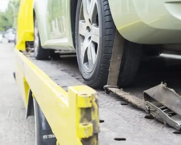 Czy komornik może zająć samochód osobie niepełnosprawnej? Auto na lawecie, zabezpieczone pasami.