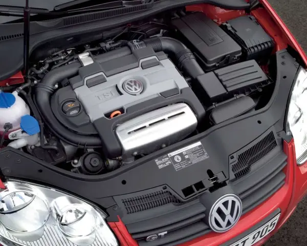 Silnik 1.4 TSI Twincharger w czerwonym Volkswagenie. Widoczne elementy układu dolotowego i chłodzenia.