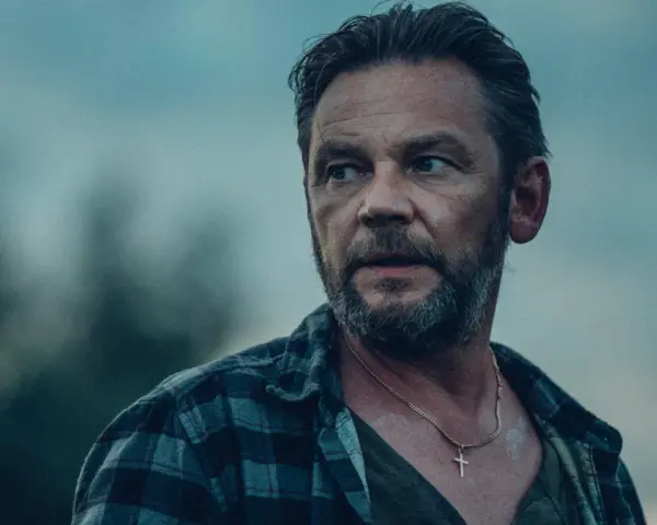 Ireneusz Czop w serialu "Kruk" jako inspektor Jakub Wesołowski. W tle niebo i zamazane drzewa.