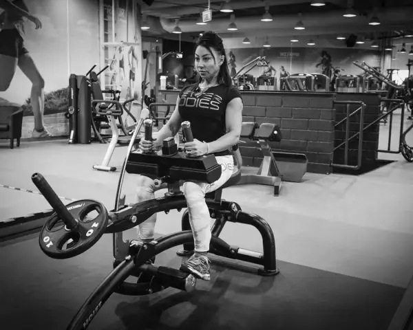Kvinna tränar sittande vadpress på gym.