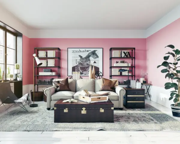 Salon z róż indyjski na ścianach. Wygodna sofa, stylowa skrzynia i regały pełne książek tworzą przytulną atmosferę.