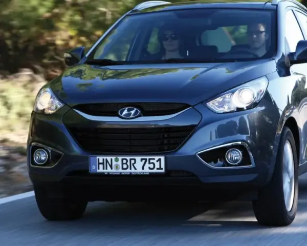 Dunkelgrauer Hyundai ix35 fährt auf einer Straße. Fahrer und Beifahrerin sind zu sehen. Mögliche Hyundai ix35 Probleme sind hier nicht ersichtlich.