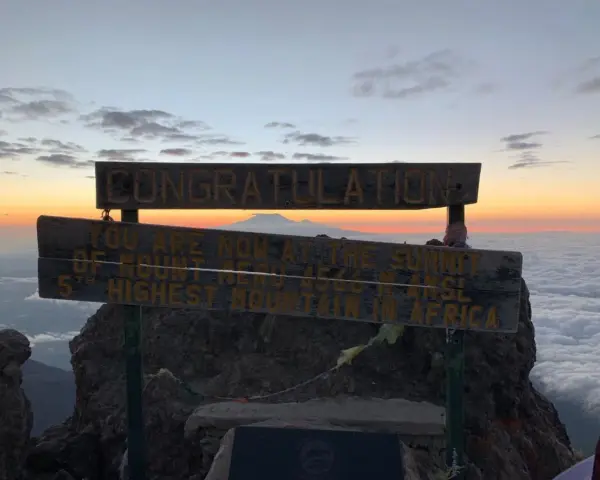 Gratulacje! Jesteś na szczycie Mount Meru, 5. najwyższej góry Afryki. Widok na morze chmur i wschód słońca zapiera dech w piersiach.