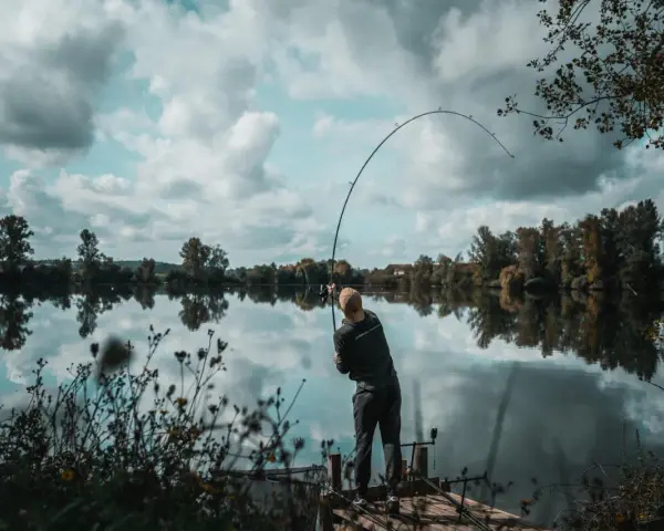 Wędkarz na pomoście, zgięta w łuk wędka świadczy o walce z rybą. Konopie na ryby to jego pasja.