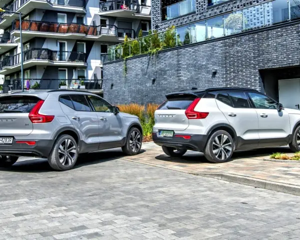 Dwa modele Volvo XC40, jeden srebrny, drugi biały, zaparkowane przed nowoczesnym budynkiem.