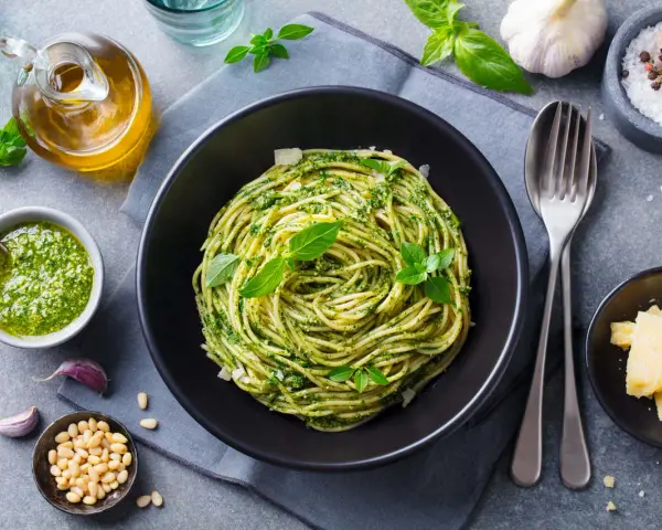 Pyszne spaghetti z pesto, idealne co na obiad zamiast mięsa. Podane z parmezanem, orzeszkami pinii i świeżą bazylią.