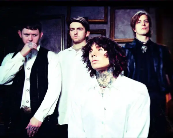 Les membres de Bring Me The Horizon posent ensemble, vêtus de blanc et de noir, dans une ambiance sombre et stylisée.