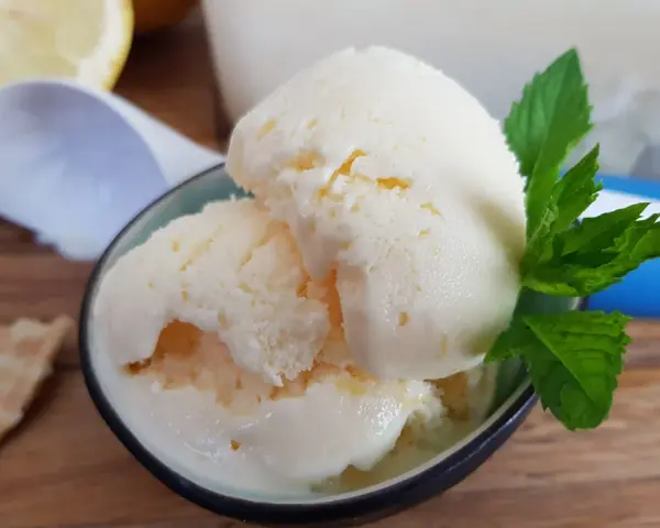 Erfrischendes zitronen joghurt eis mit Minze und einem Waffelstück auf Holztisch.