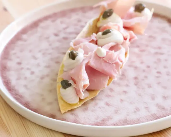 Delizioso antipasto con pane carasau, prosciutto cotto, crema e capperi. Un'idea per ricette veloci e gustose.