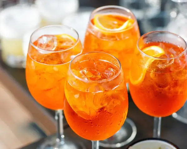 Cztery orzeźwiające drinki Aperol Spritz z lodem i plasterkami pomarańczy. Idealny aperol przepis na letnie popołudnie.