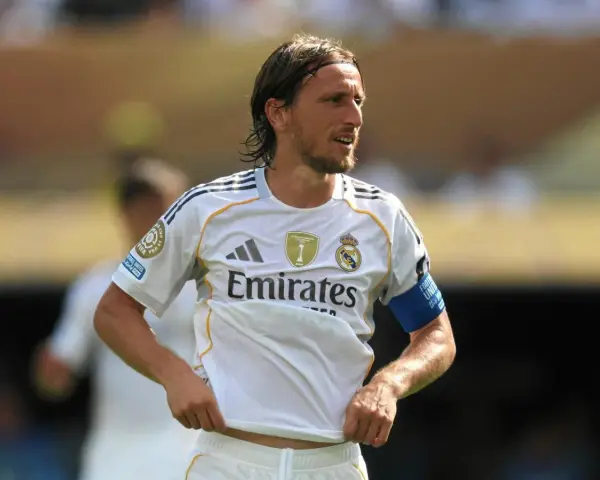 Luka Modrić w białej koszulce Realu Madryt, gdzie gra, z opaską na ramieniu.