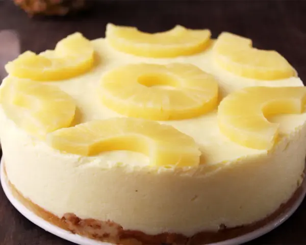 Tarta de piña cremosa, decorada con rodajas y trozos de piña fresca. ¡Un postre tropical irresistible!