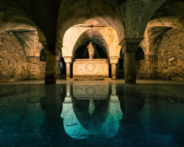 Sotterranei di Venezia misteriosa, con statue e riflessi sull'acqua.
