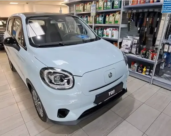 Jasnoniebieski Leapmotor T03 stoi w salonie samochodowym obok półek z akcesoriami.