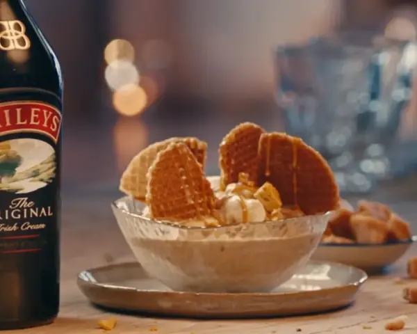 Baileys Eis Rezept: Cremiges Eis mit Karamell und Waffeln, daneben eine Flasche Baileys.