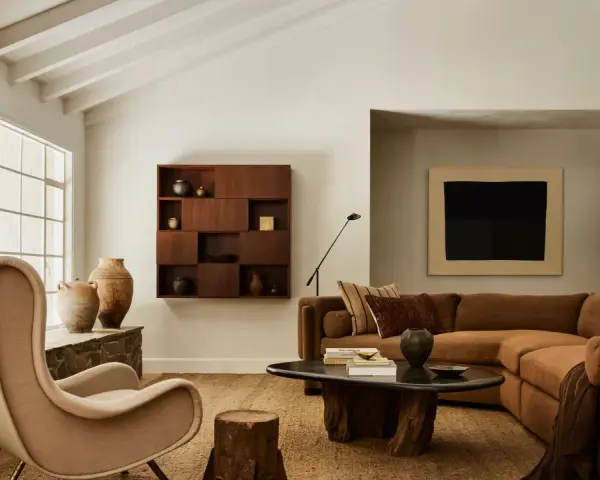 Un acogedor salón con chimenea de piedra, sillón de tela, sofá marrón y mesa de centro de madera. El arte de pared y las cerámicas añaden un toque de estilo chino hogar.