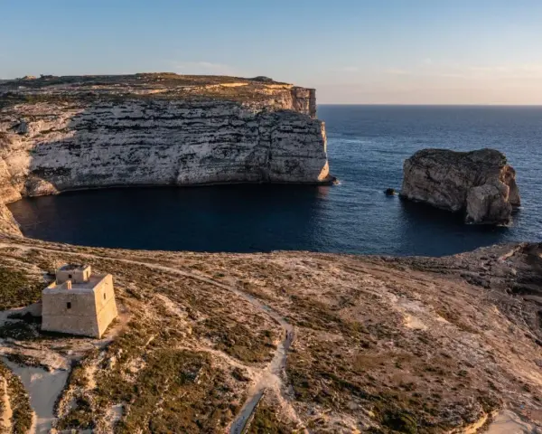Malta pogoda w styczniu: słoneczny dzień nad zatoką z wieżą strażniczą i skalistymi klifami.