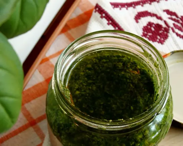 Słoik domowego pesto z bazylii, obok świeże liście. Idealne do makaronu!