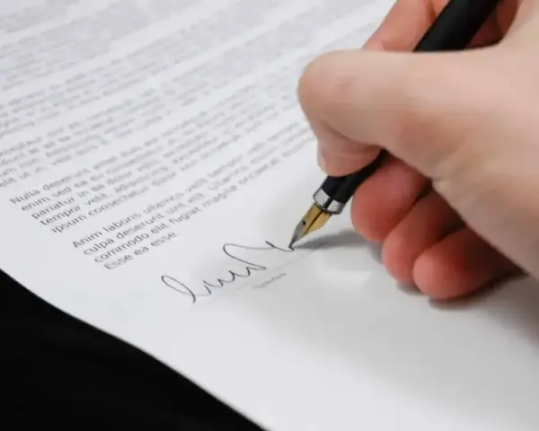 Dłoń podpisuje dokument, być może oświadczenie o odrzucenie spadku.