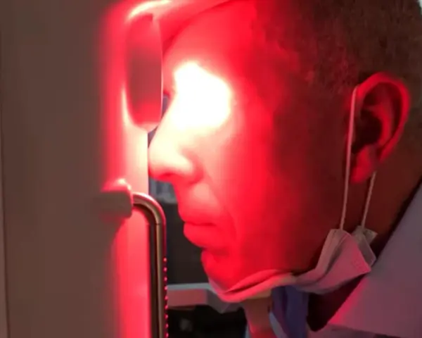 Uomo con maschera chirurgica sotto il mento, riceve fotobiomodulazione facciale. Attenzione alle fotobiomodulazione controindicazioni.