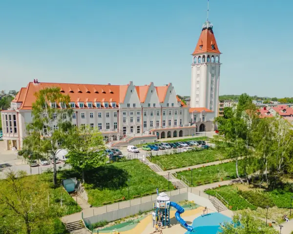 Władysławowo: okazały budynek z wieżą, dawny dom rybaka, otoczony zielenią i placem zabaw.