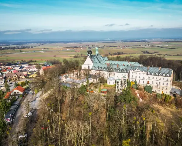 Widok z lotu ptaka na klasztor na świętej górze, otoczony lasem i miasteczkiem.