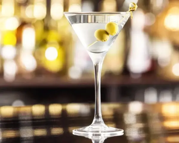 Klasyczny martini dry przepis: schłodzony gin, odrobina wermutu i dwie oliwki. Idealny drink na wieczór.