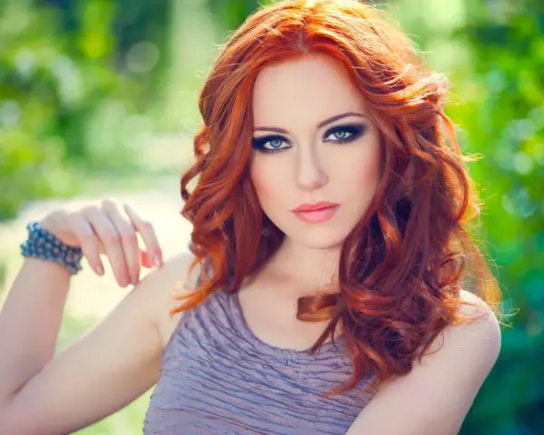 Une femme aux cheveux roux et au maquillage smoky eyes parfait, idéal pour un tuto smoky eyes débutant.