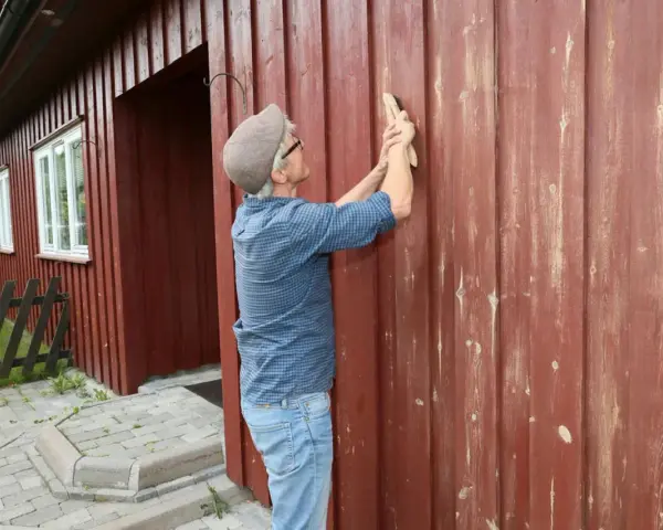 Man slipar fasaden innan målning.
