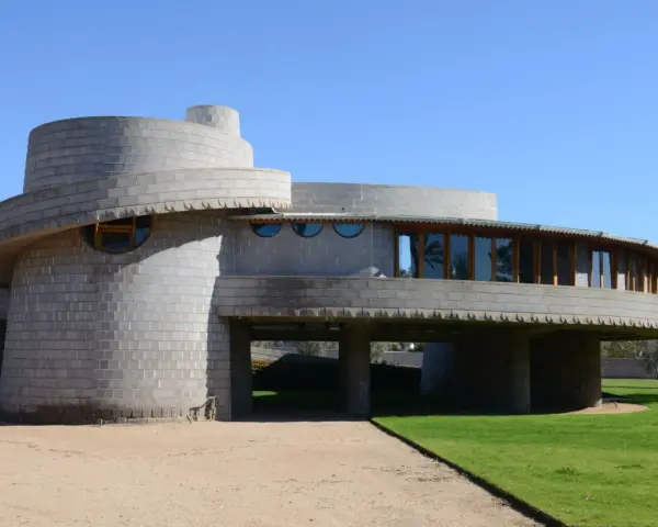 Bâtiment circulaire en béton, exemple des structures conçues par Frank Lloyd Wright, avec des fenêtres rondes et une façade en gradins.