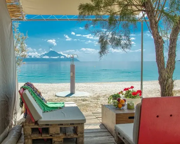 Relaks przy plaży w Armenistis Camping. Leżaki, stolik z owocami i widok na turkusowe morze.