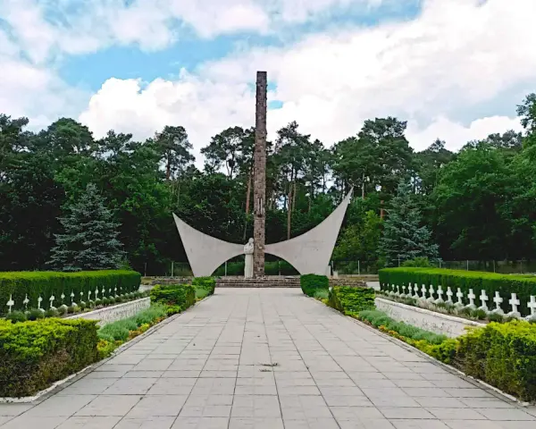 Pomnik i rzędy białych krzyży na cmentarzu w Siekierkach.
