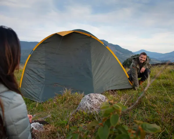Mann und Frau biwakieren in Deutschland. Sie bauen ein Zelt in den Bergen auf, die Landschaft ist wunderschön.