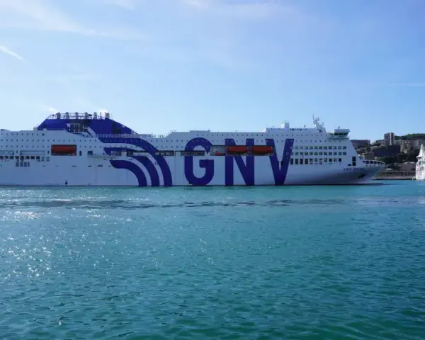 Ogromny prom GNV Orion czeka na pasażerów, by zabrać ich w podróż na Sycylię. W tle widać port i wzgórza.