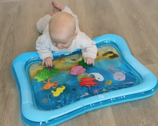 Niemowlę bawi się na macie wodnej dla niemowląt z morskimi stworzeniami.
