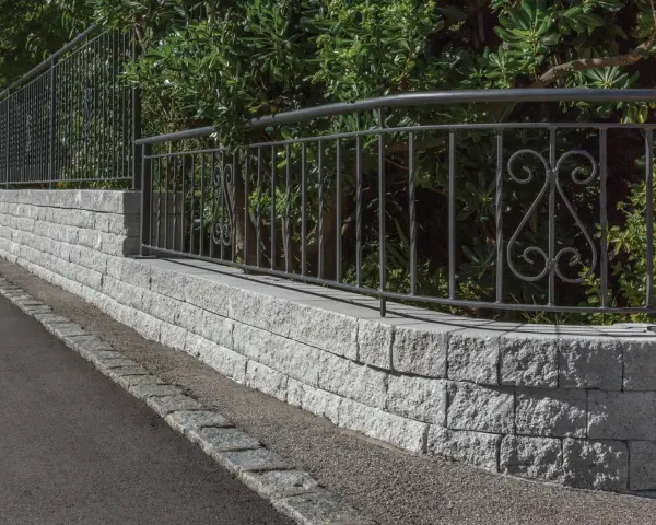 Muro in pietra grigia con ringhiera in ferro battuto, un'ottima idea per muri di recinzione moderni ed eleganti.