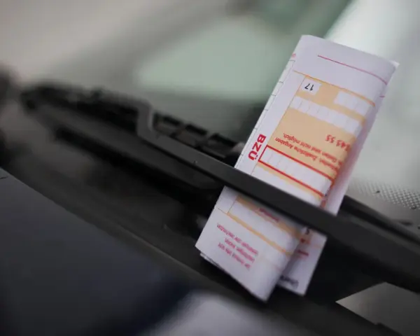 Ein Strafzettel unter dem Scheibenwischer. Parken ohne Parkschein kostet Geld und Ärger.