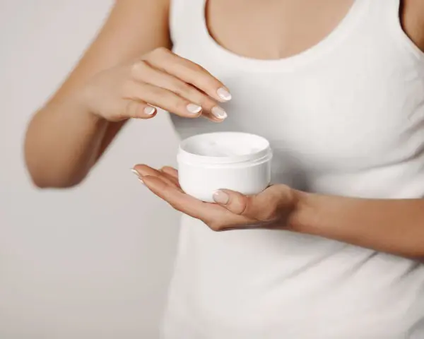Manos aplicando crema para suavizar la piel y tratar la queratosis pilaris.