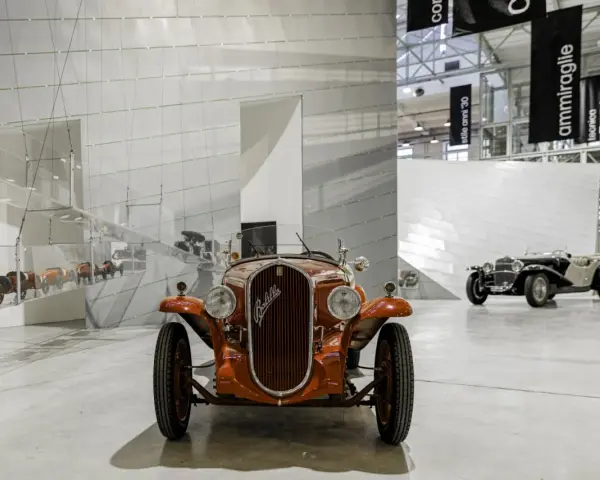 Pomarańczowy Fiat Balilla z 1933 roku na wystawie w Muzeum Fiata w Turynie. W tle inne zabytkowe samochody.
