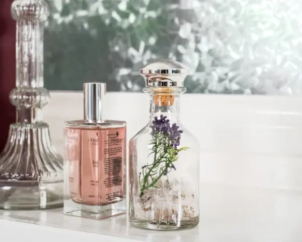 Eleganckie perfumetki męskie w szklanych buteleczkach, jedna z lawendą, obok ozdobnego świecznika.