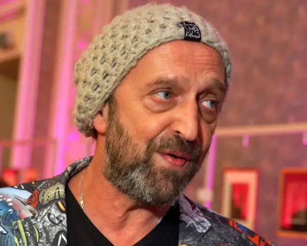 Nikodem Chabior w beżowej czapce i kolorowej kurtce, z zarostem, patrzy w bok.