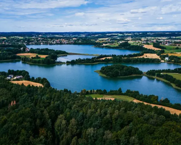 Malownicze jeziora i lasy tworzą tajemnicze miejsca na Kaszubach. Widok z lotu ptaka ukazuje spokojne wody, zielone wyspy i pola uprawne.