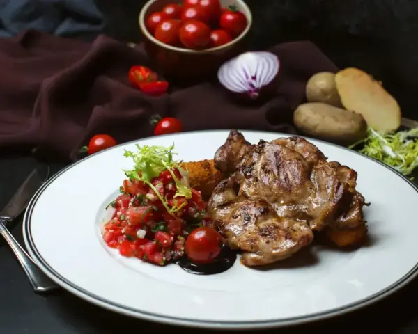 Soczysty udziec jagnięcy z salsą pomidorową i ziemniakami.
