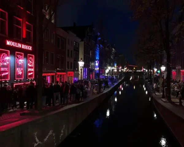 Nocna czerwona ulica Amsterdamu z kanałem i neonami.