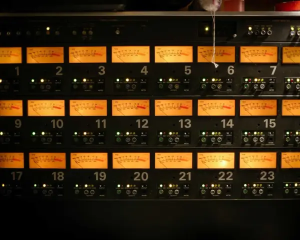 Panneau d'équipement audio avec 24 indicateurs VU orange, chacun affichant un niveau sonore, certains proches de 0 dB, équivalent à 64 décibels.