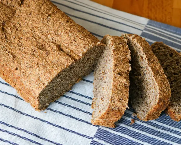 Ein frisch gebackenes vollkornbrot mit hefe, aufgeschnitten auf einem gestreiften Tuch.