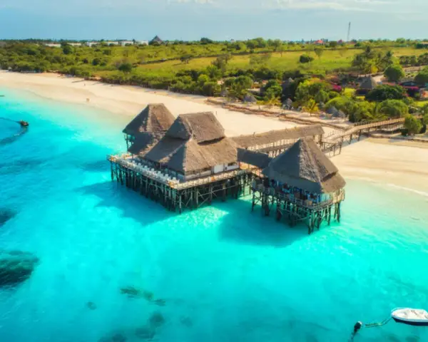 Rajskie plaże i turkusowa woda, idealne tanzania atrakcje. Domki na palach w tropikalnym otoczeniu.