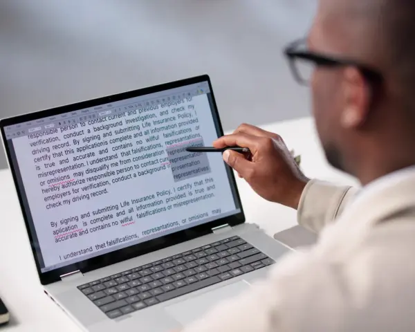 Un homme examine un document sur un écran d'ordinateur, soulignant des passages pour apprendre comment reconnaître une pièce fautée.