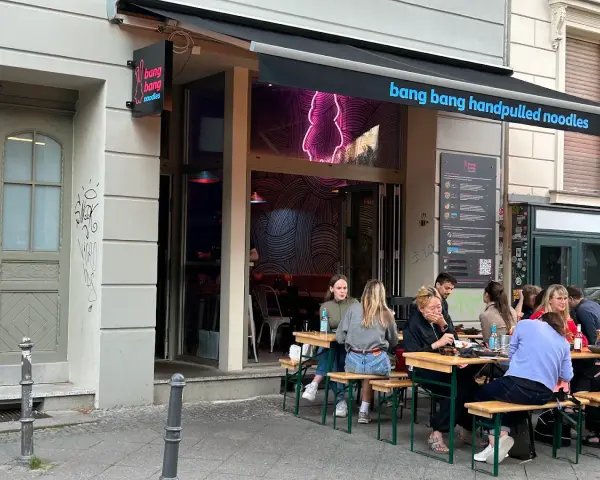 Menschen genießen das Essen vor dem Restaurant "bang bang noodles berlin".
